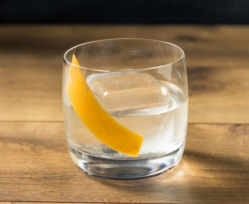Glass tumbler filled with a tequila Old Fashioned recipe, ice, and lemon peel garnish.