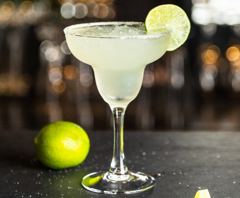 Margarita glass filled with a damiana margarita recipe with salt rim and lime slice for garnish.